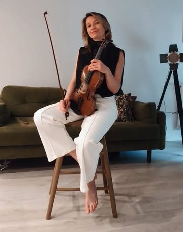 Anastasia seated with her violin